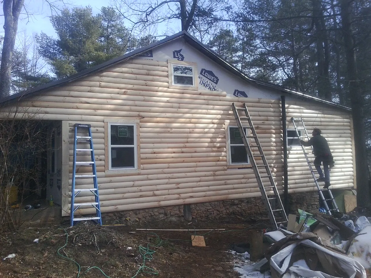 Ladders set against fresh log siding during an exterior remodel in Atkinson