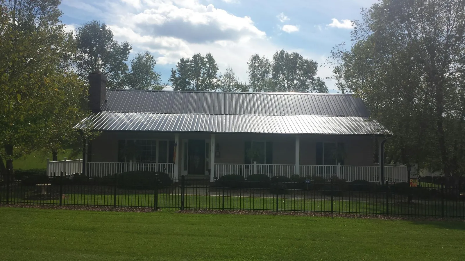 Gray metal roof on a brick ranch with a full width front porch — Gutter Guard Installation work by our crew in Atkinson